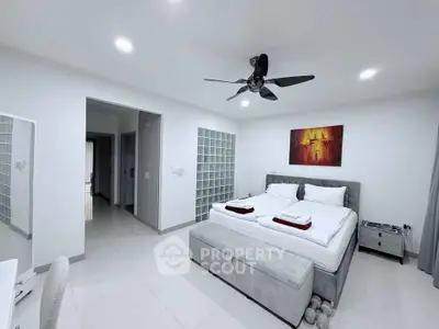 Spacious modern bedroom with elegant decor and ceiling fan, perfect for relaxation.
