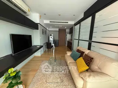 Modern living room with sleek design, featuring a comfortable sofa, glass coffee table, and wall-mounted TV.