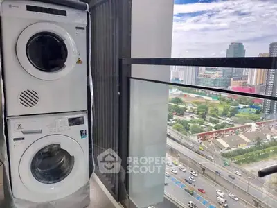 Modern balcony with washer and dryer overlooking cityscape and highway view.