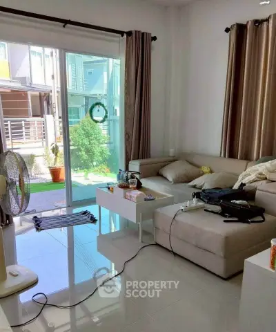 Bright living room with modern furniture and large sliding glass doors opening to a garden view.