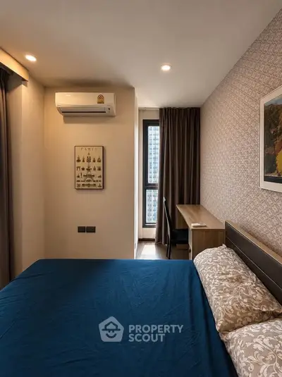 Cozy bedroom with modern decor and city view, featuring a comfortable bed and work desk.
