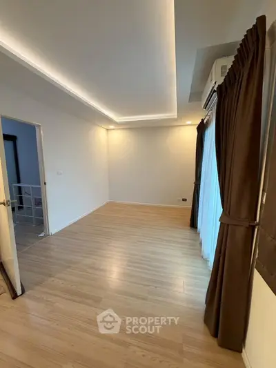 Spacious empty room with wooden flooring and elegant ceiling lights, perfect for customization.