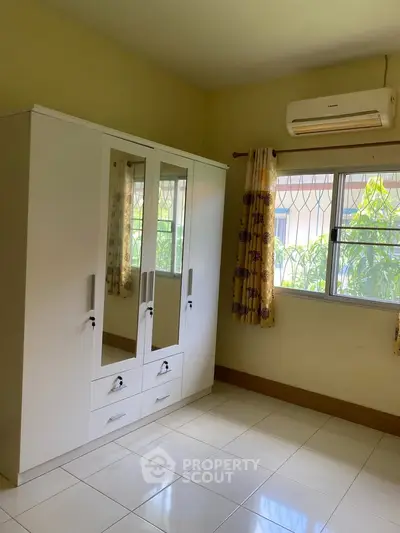 Bright bedroom with white wardrobe and air conditioning unit.