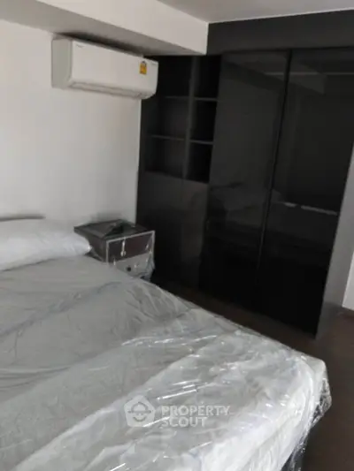 Modern bedroom with sleek black wardrobe and air conditioning unit, perfect for comfortable living.