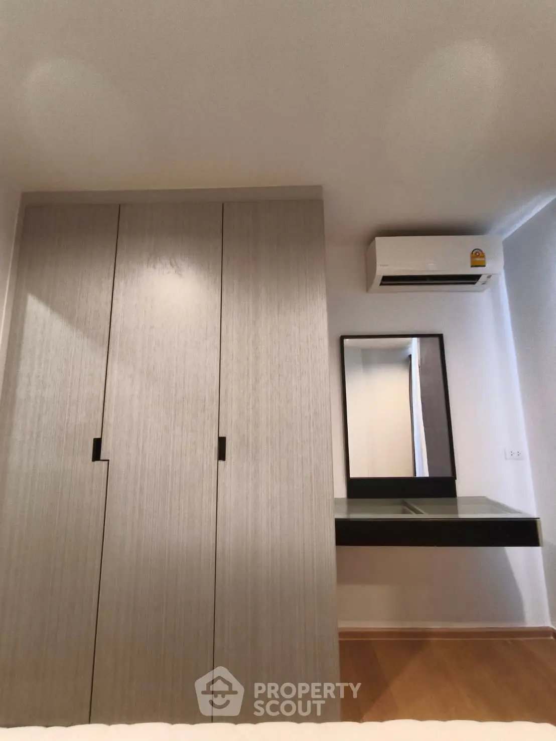 Modern bedroom with sleek wardrobe and air conditioning unit, perfect for comfortable living.