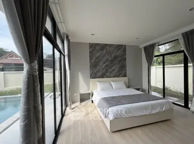 Luxurious bedroom with pool view and modern decor in a serene setting.