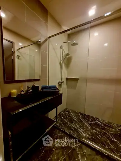 Luxurious modern bathroom with sleek black marble flooring and glass shower enclosure.