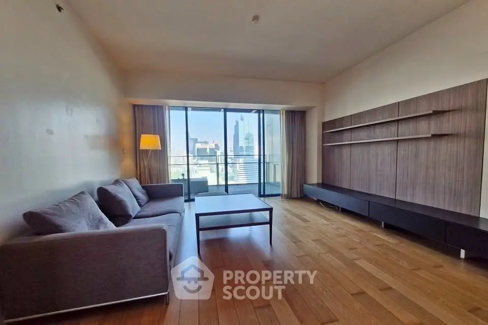 Spacious living room with modern furnishings and city view balcony in luxury apartment.