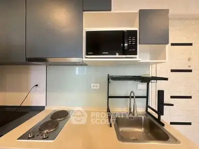 Modern kitchen with sleek cabinets, electric stove, and built-in microwave in a compact layout.