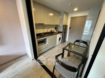 Modern kitchen with sleek cabinets, washing machine, and dining area in compact apartment.