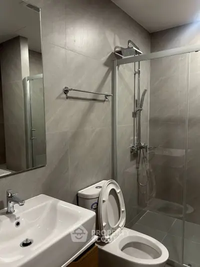 Modern bathroom with glass shower and sleek fixtures in contemporary apartment.