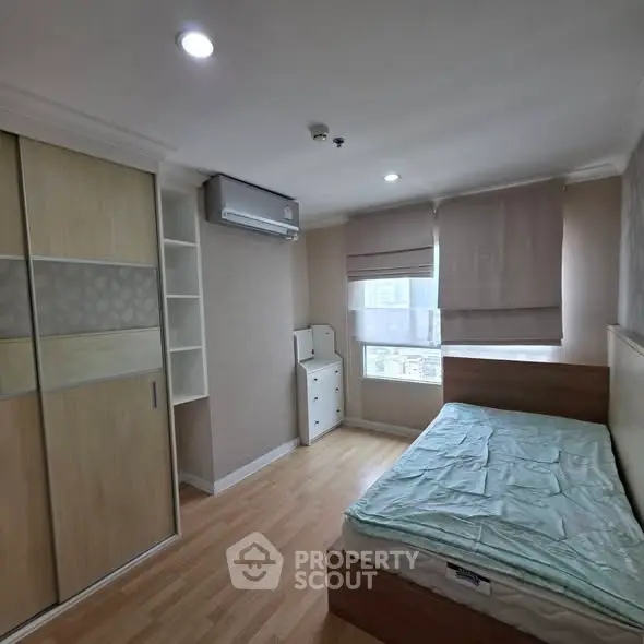 Cozy bedroom with wooden flooring, built-in wardrobe, and large window for natural light.