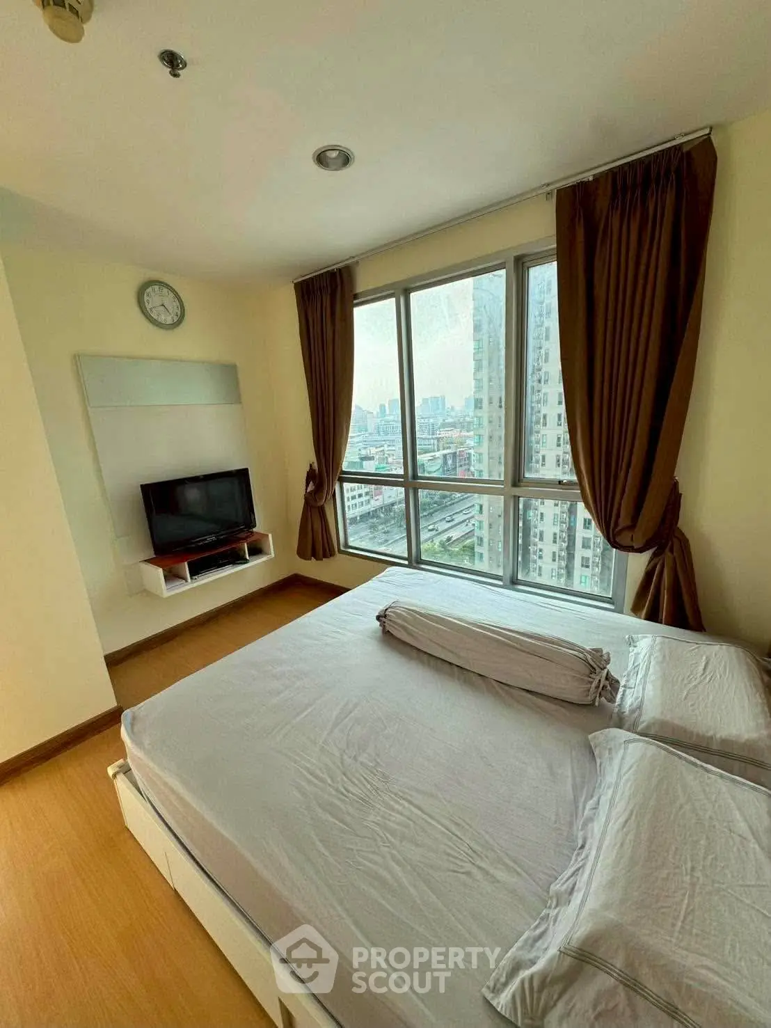 Spacious bedroom with city view and modern furnishings in high-rise apartment