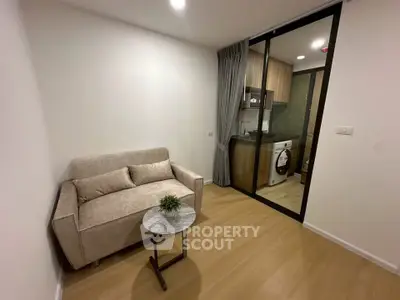 Modern compact living room with cozy sofa and open kitchen layout in a stylish apartment.