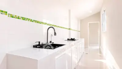 Sleek modern kitchen with white cabinetry and black fixtures, featuring a gas stove and stylish backsplash.