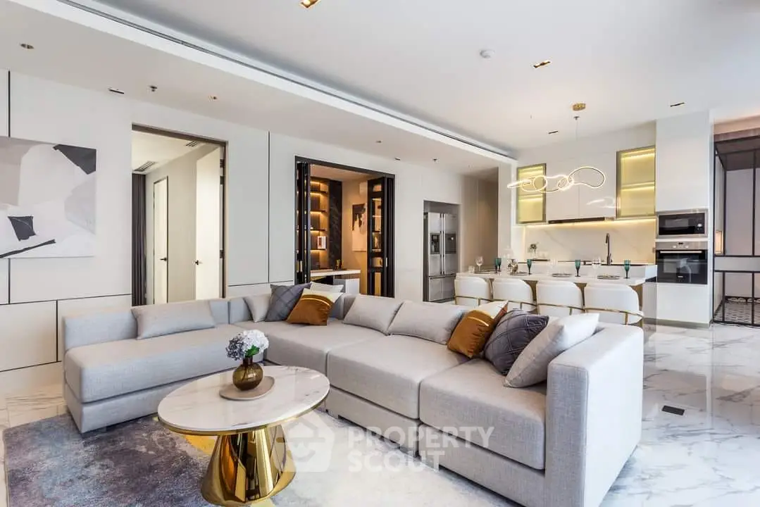 Luxurious open-plan living space with elegant sectional sofa, modern art, and seamless transition to a state-of-the-art kitchen, perfect for entertaining.