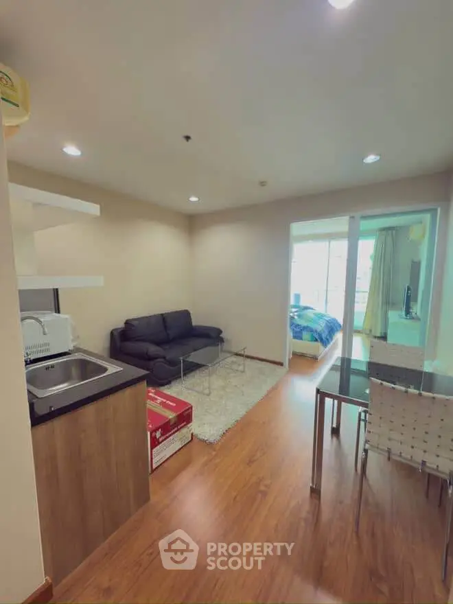 Modern open-plan living room with cozy seating and dining area, featuring sleek wooden flooring and natural light.