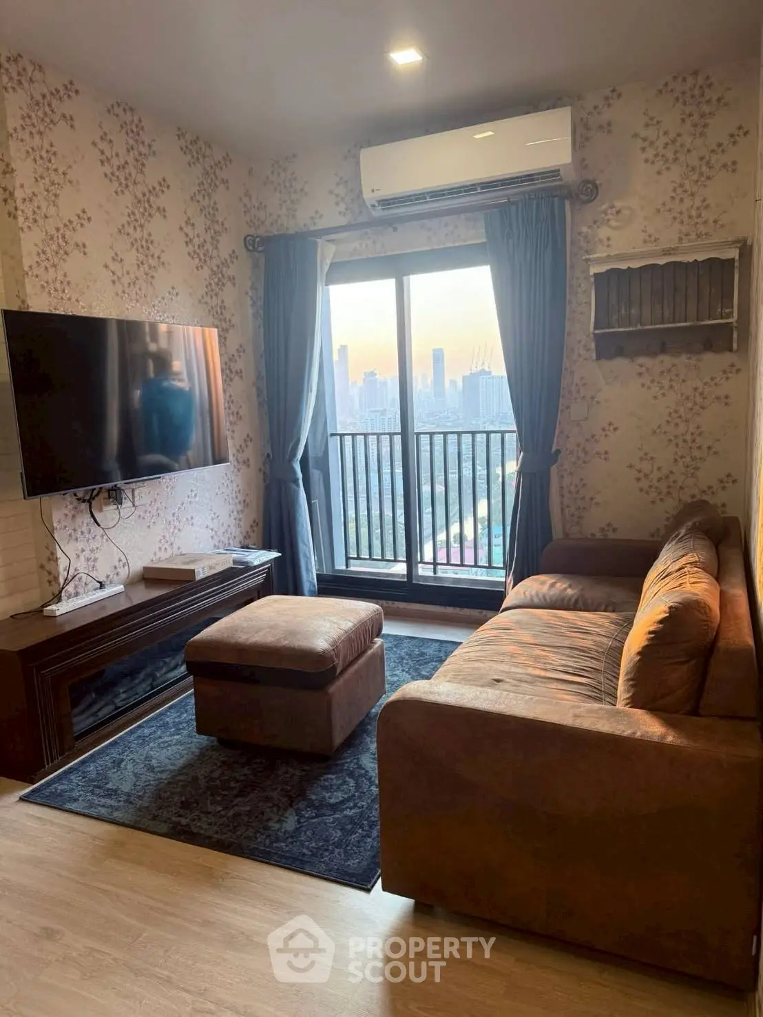 Cozy living room with city view, featuring a large TV and comfortable seating.