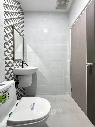 Modern bathroom with stylish geometric tiles and sleek fixtures.