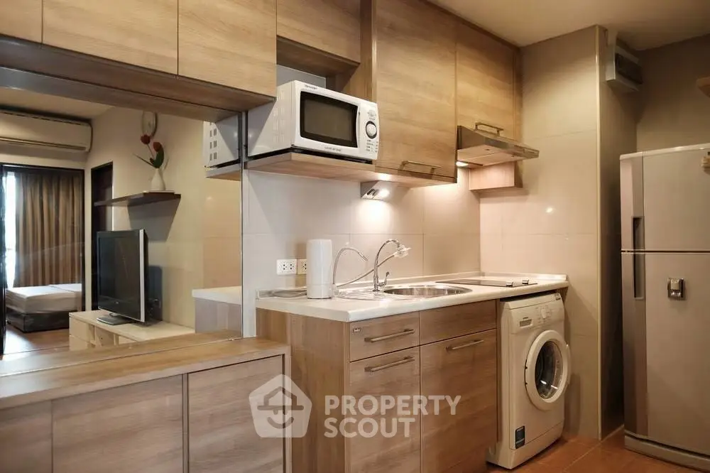 Modern compact kitchen with wooden cabinets and built-in appliances in cozy apartment.