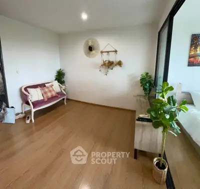 Spacious living room with elegant decor and wooden flooring, featuring a cozy sofa and modern plants.