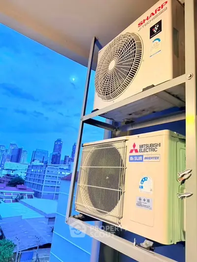 City view with air conditioning units on a balcony, showcasing urban living convenience.