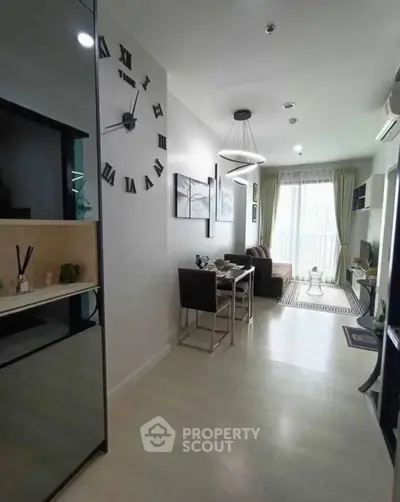 Modern living room with stylish decor and natural light, featuring a dining area and wall clock.