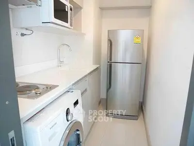 Modern compact kitchen with appliances including fridge, microwave, and washing machine.