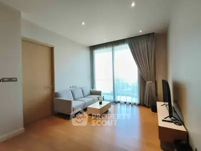 Modern living room with sleek furniture and large window offering natural light.