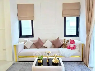 Elegant living room with plush sofa, chic decor, and natural light through large windows.