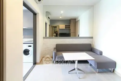 Modern living room with sleek furniture and washing machine in open layout.
