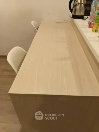 Modern kitchen with sleek wooden breakfast bar and stylish chairs.