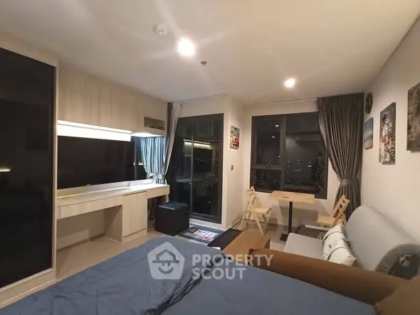 Modern studio apartment with stylish decor and city view, featuring a cozy living area and large windows.