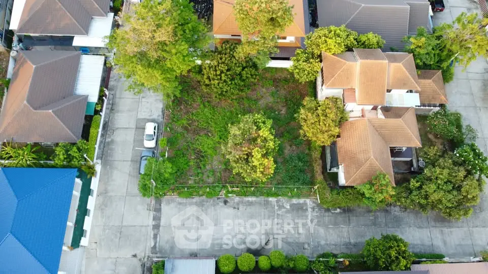 Aerial view of residential neighborhood with houses and empty plot for development.