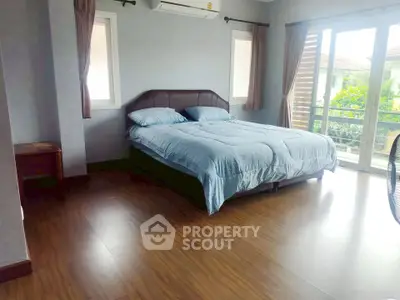 Spacious bedroom with large windows and wooden flooring