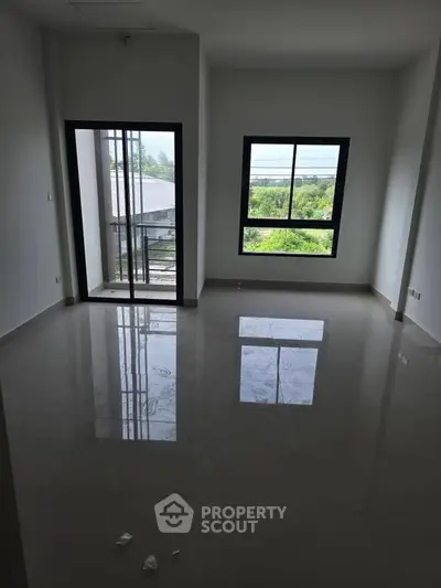 Spacious living room with large windows and balcony access, offering natural light and scenic views.