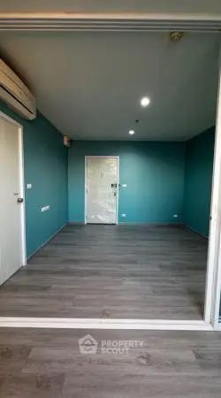Spacious empty room with teal walls and wooden flooring, ideal for customization.