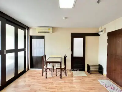 Spacious living room with modern furniture and wooden flooring, featuring ample natural light.