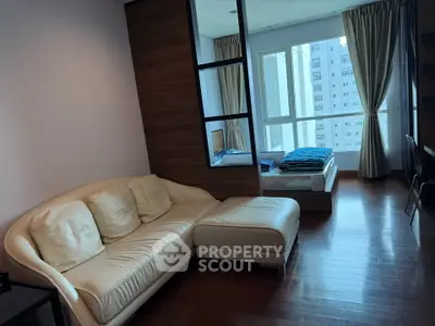 Modern studio apartment with cozy living area and large windows offering city views.