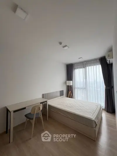Spacious bedroom with modern furnishings and large window view