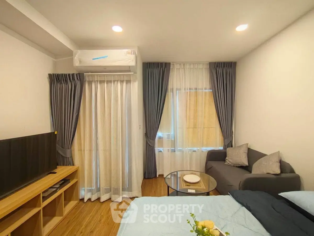 Cozy living room with modern decor, featuring a comfortable sofa, flat-screen TV, and elegant curtains.
