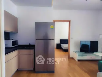 Modern apartment interior with kitchen and living area featuring sleek appliances and wooden flooring.