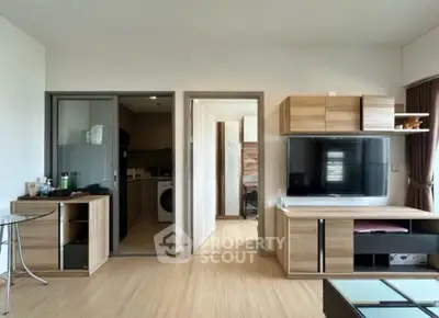 Modern living room with wooden furniture and TV, open view to kitchen area