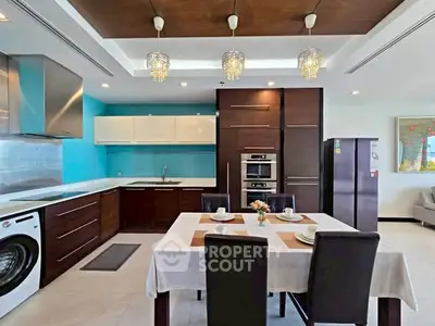 Modern kitchen with dining area, featuring sleek cabinetry, washing machine, and elegant lighting.