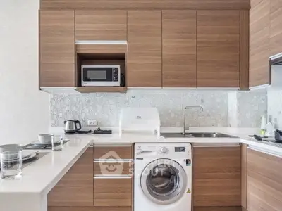 Modern kitchen with wooden cabinets, washing machine, and sleek appliances.