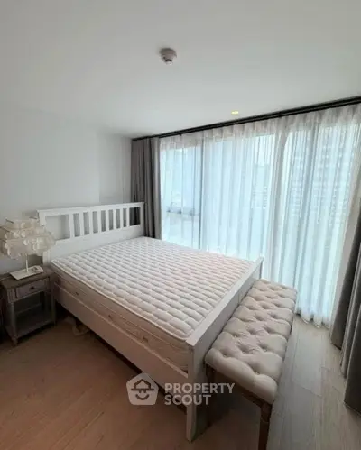 Spacious bedroom with large windows and elegant furnishings in modern apartment.