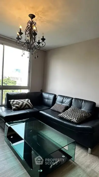 Stylish living room with black leather sofa and elegant chandelier