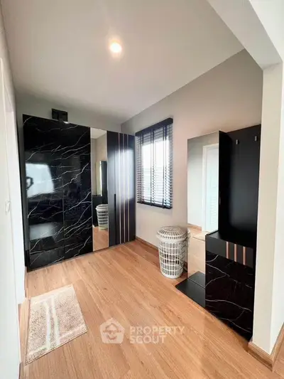 Modern bedroom with sleek black wardrobe and wooden flooring