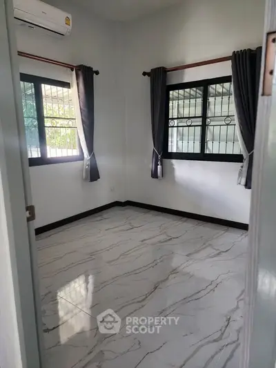 Spacious room with marble flooring and large windows, perfect for natural light.