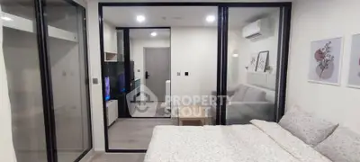 Modern bedroom with glass partition and cozy living area in stylish apartment.